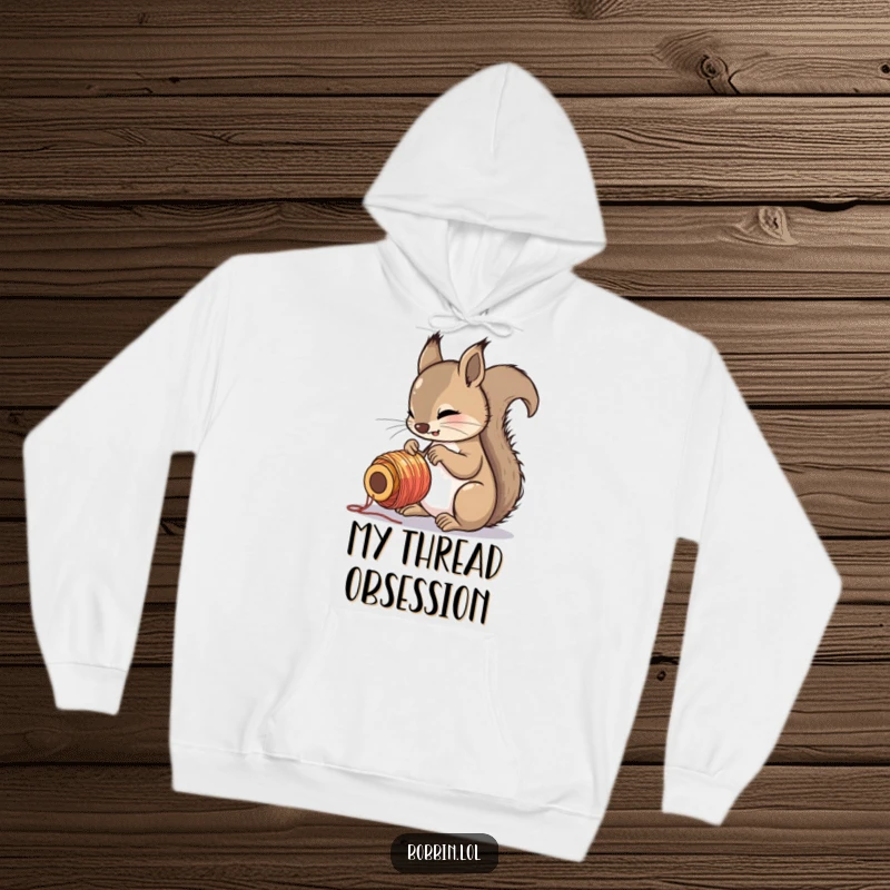 Funny squirrel intensely focused on a colorful spool of thread, featured on a warm and humorous hoodie.